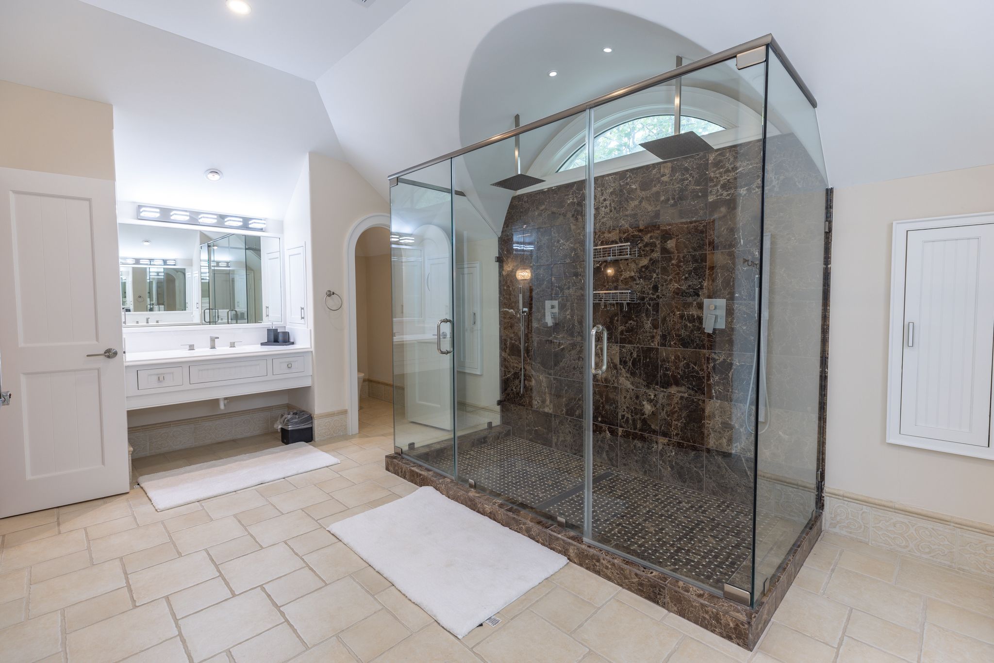 Stone-tiled walk-in shower in a secondary suite bath