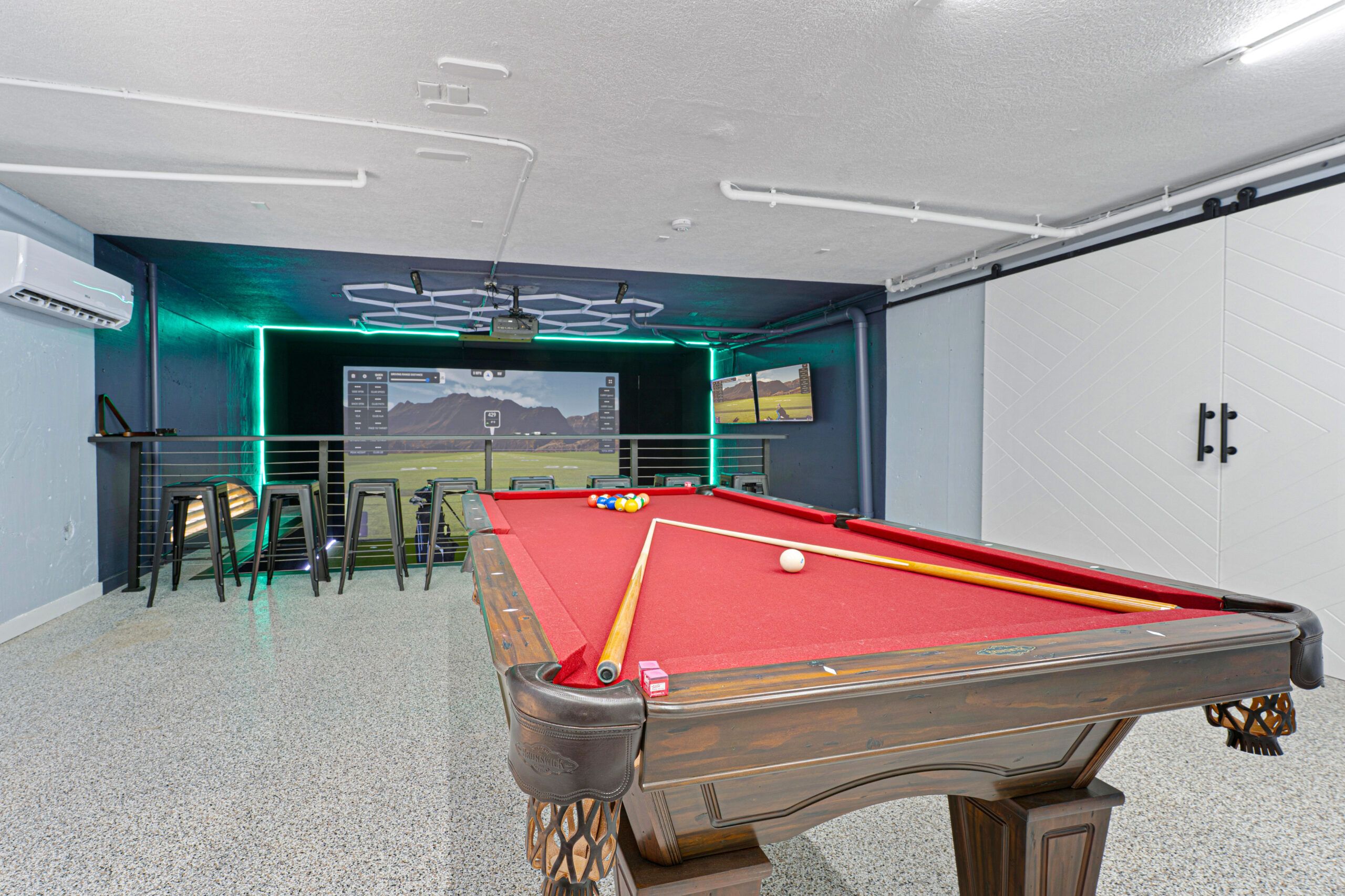 Game room with red-felt pool table and the golf simulator beyond