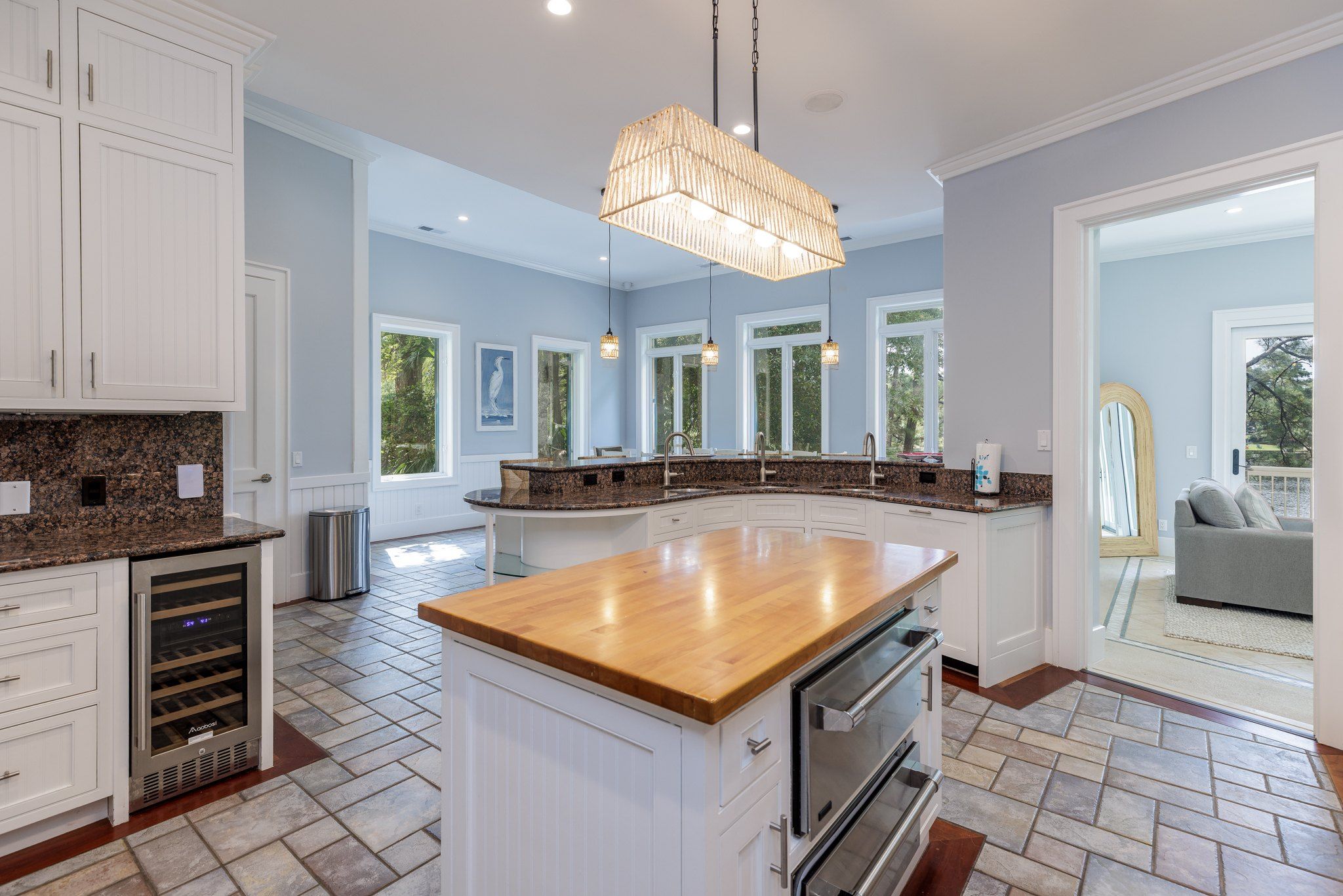Wide view of the chef’s kitchen with the island, wine fridge, and range
