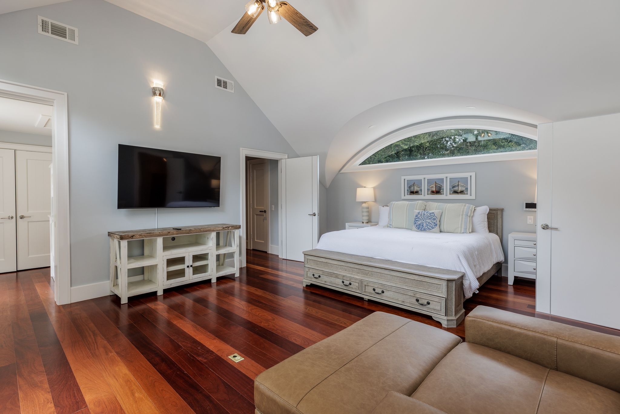 Primary suite under a vaulted ceiling with a tall arched window