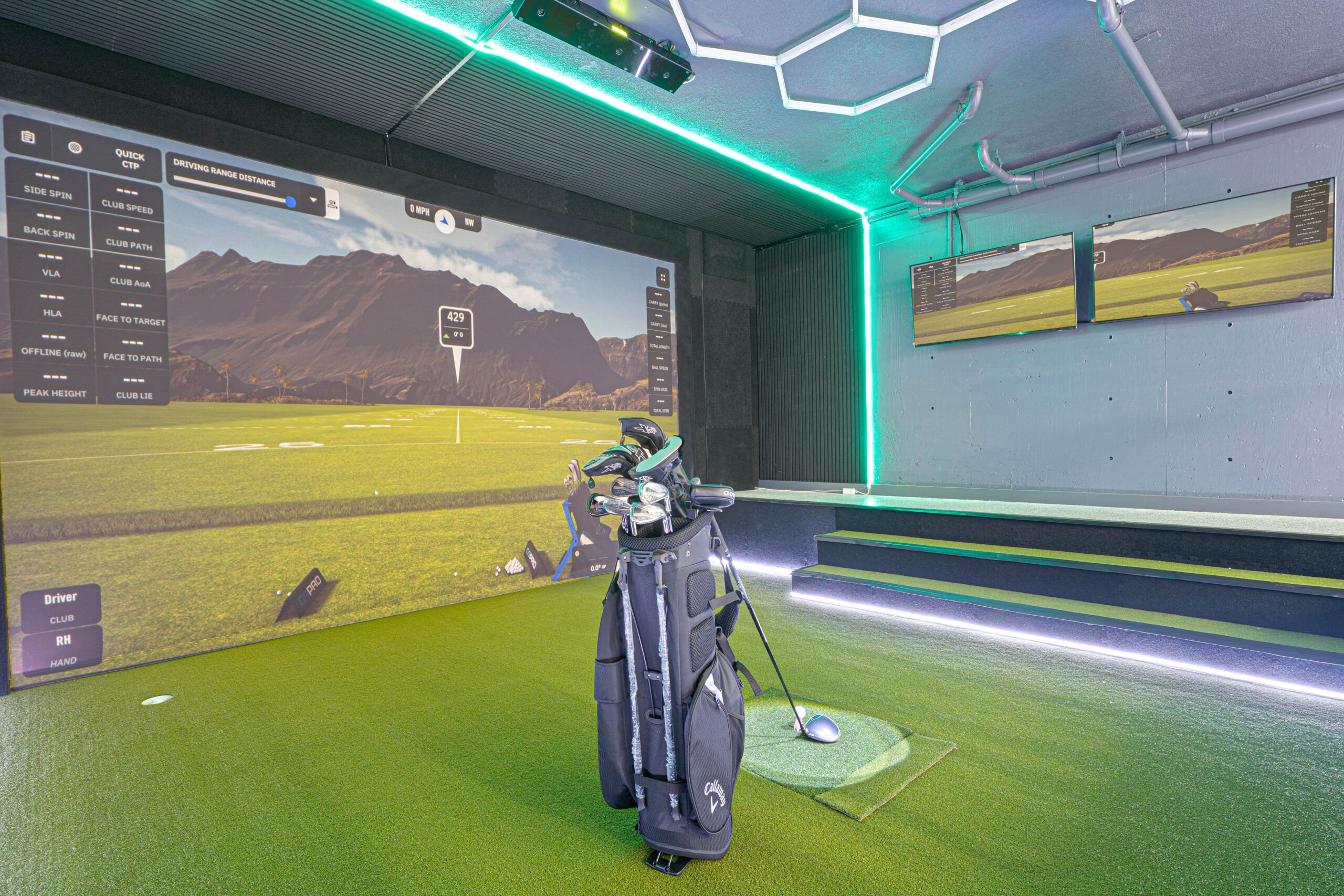 Golf simulator hitting bay with screens set up for evening play at the estate