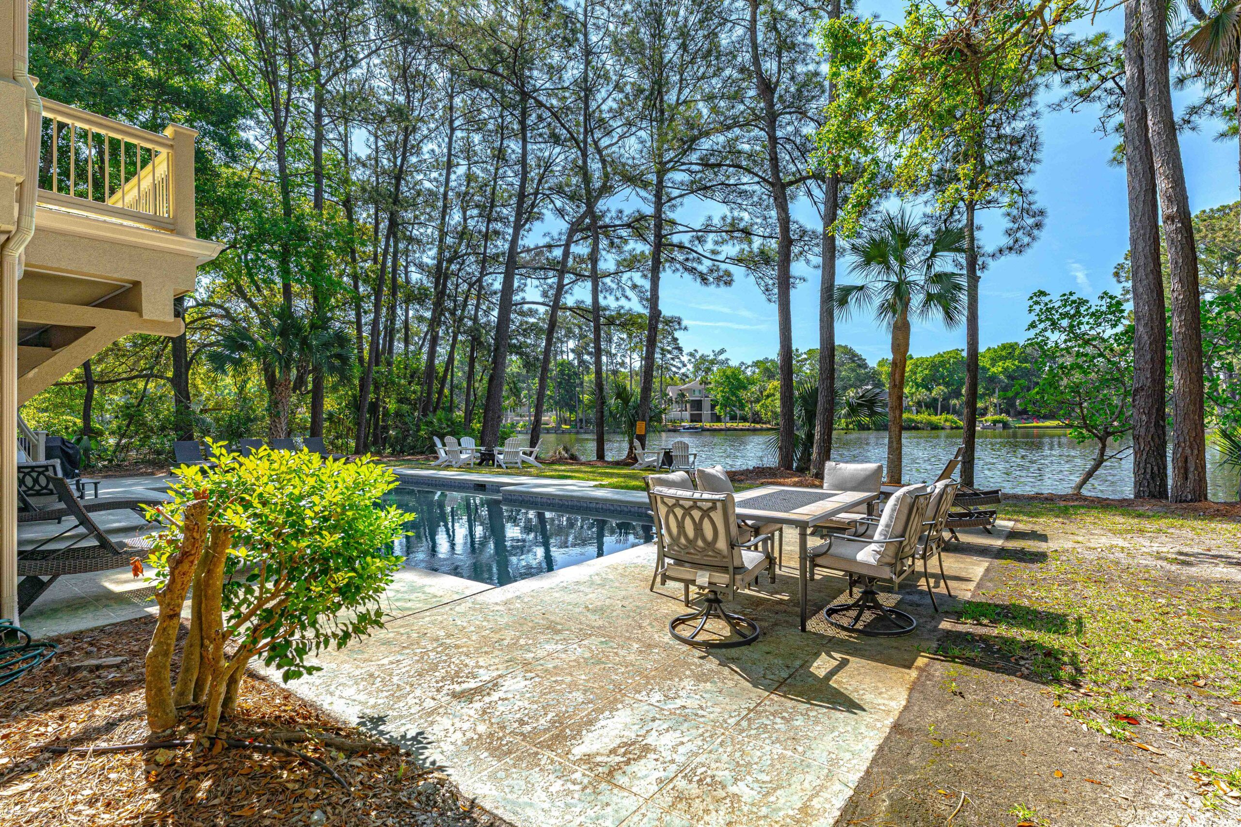 Poolside patio dining beside the private pool with the lagoon beyond at the Palmetto Dunes estate